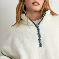 Close-up of cream sherpa fleece half zip neckline with green gingham trim and zipper