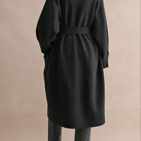 Back view of black belted long coat with relaxed silhouette and stand collar