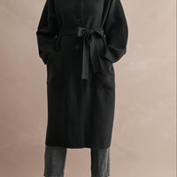 Women's black stand collar long coat with button-front closure, self-tie waist belt, and oversized patch pockets