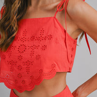 Red crop top with intricate lace detailing on a gray background