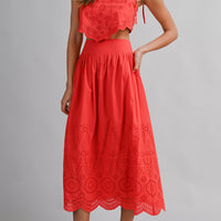 Woman wearing a red lace dress with white sneakers on a gray background