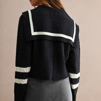 Back view of women's navy cable knit cardigan with oversized sailor collar and ivory stripe trim