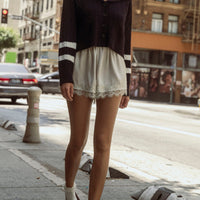 Women's cropped navy cable knit cardigan with sailor collar styled with ivory lace trim shorts and ballet flats