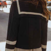 Woman wearing navy sailor collar cable knit cardigan with ivory contrast stripes and lace trim shorts