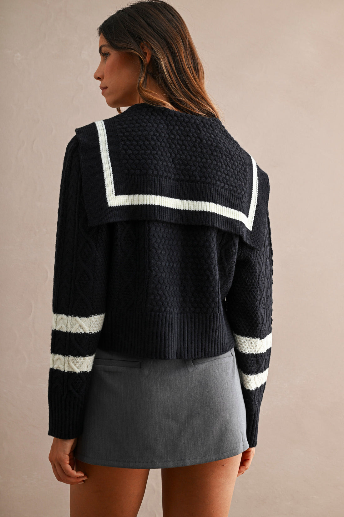 Back view of women's navy cable knit cardigan with oversized sailor collar and ivory stripe trim